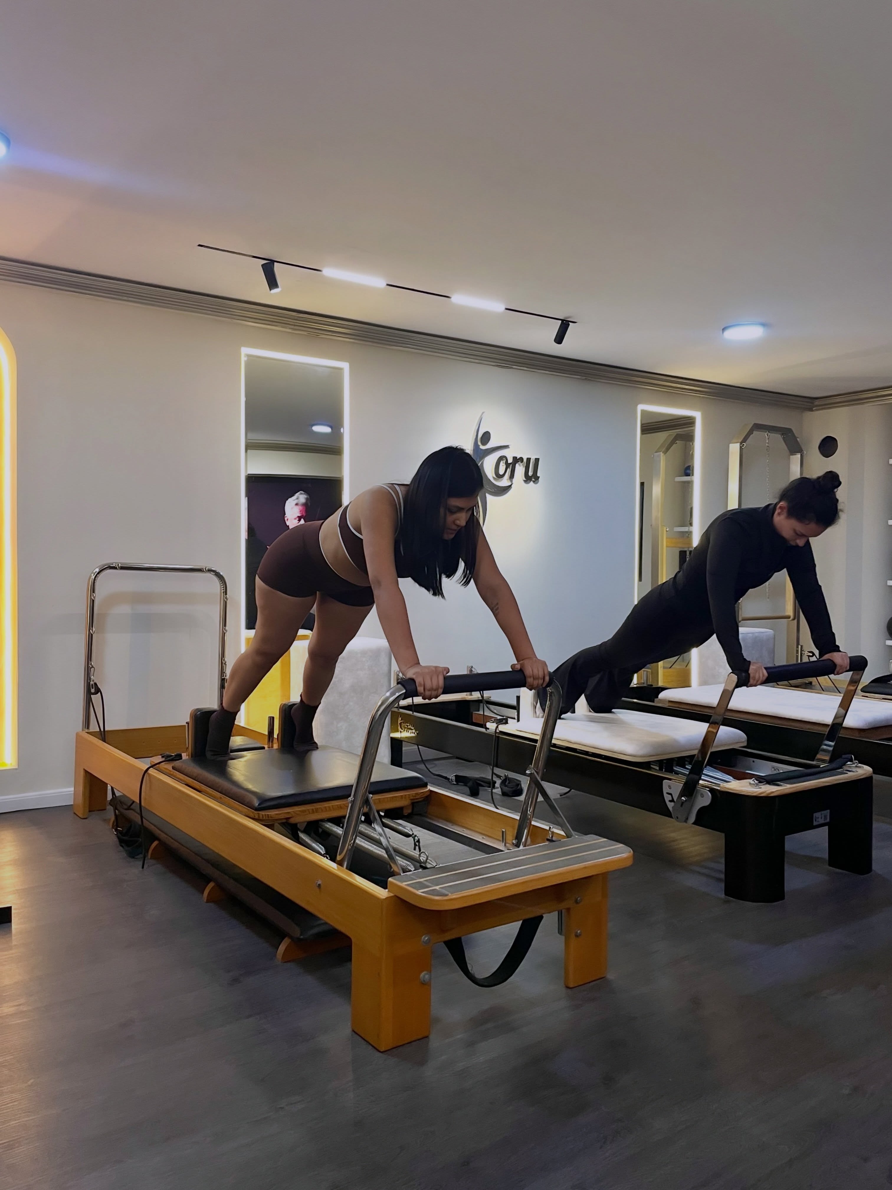 Dos personas practicando Pilates en reformers en Koru Studio